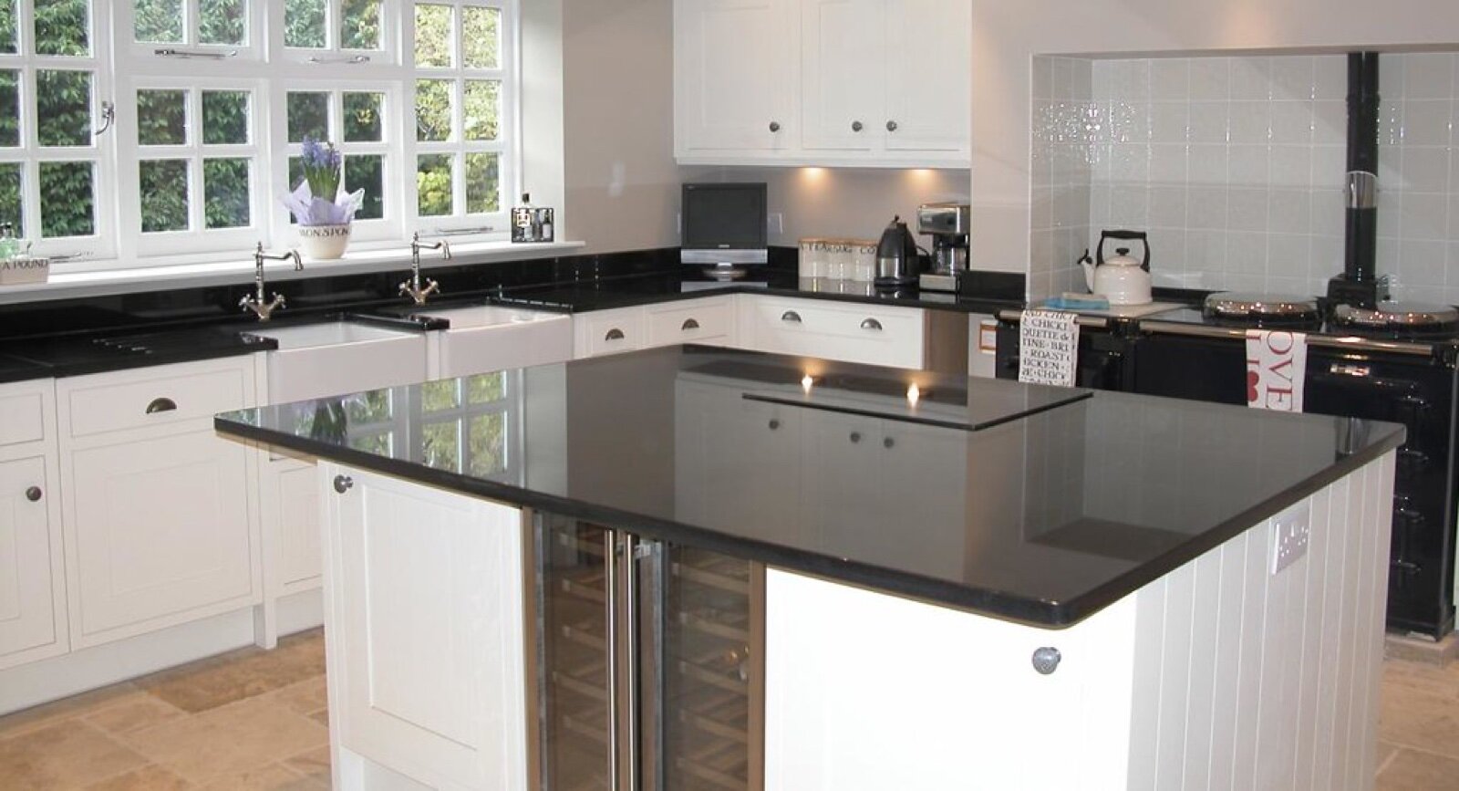 A white kitchen with a central island and dark granite worktop