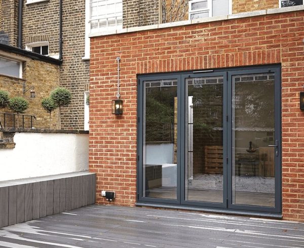 Grey aluminium bi-folding doors in a red brick rear extension opening onto a decked patio