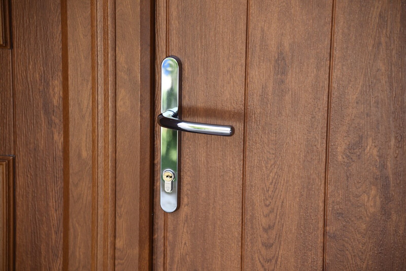Handle and euro cylinder on a brown woodgrain composite front door