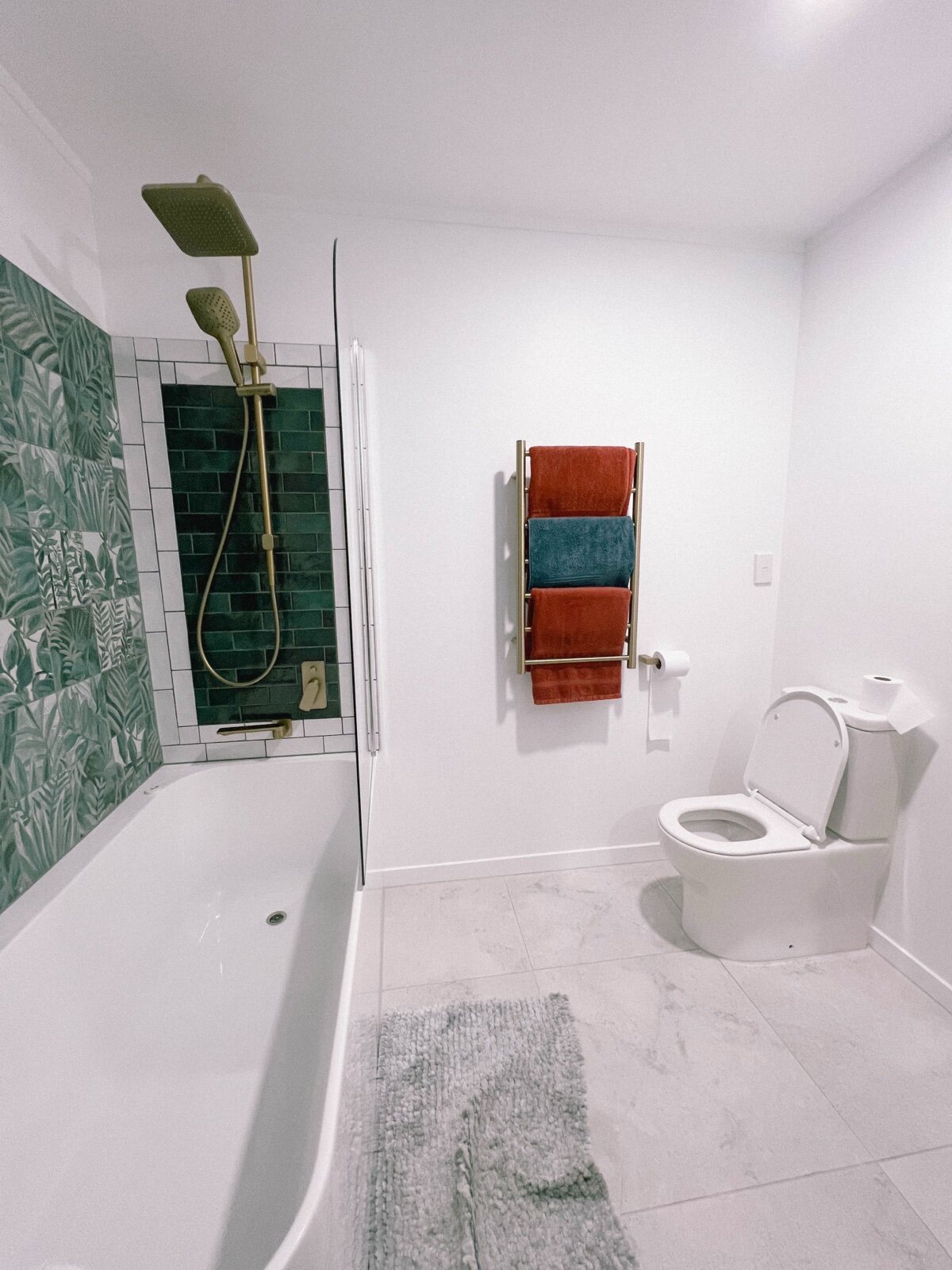 Small bathroom with fittings arranged along one wall, shower over bath and WC opposite
