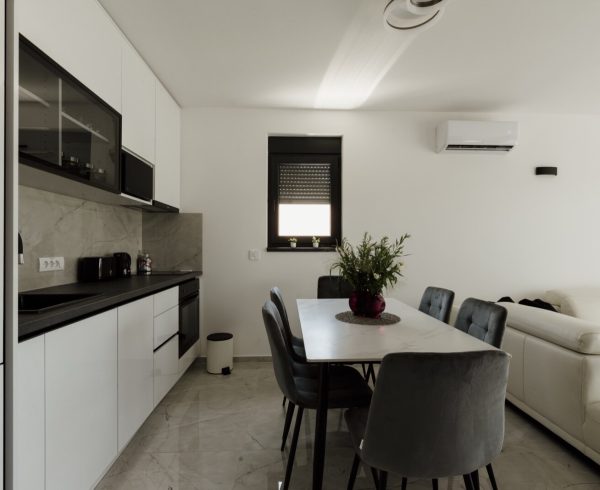 Open plan kitchen diner with white units running into a dining table and seating area
