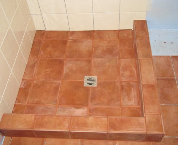 A tiled shower floor laid to a fall around a central drain