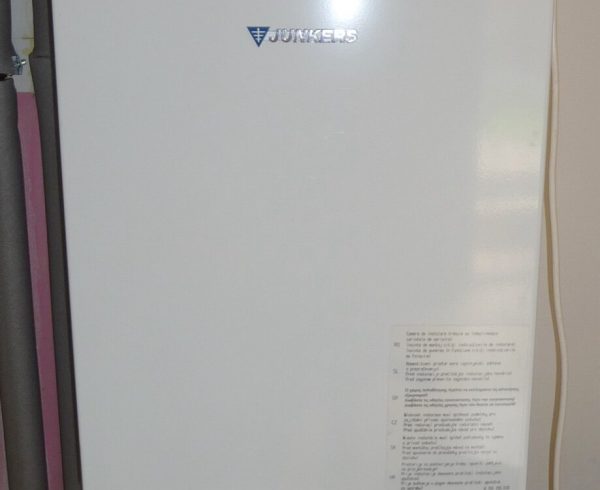 White wall-hung gas combi boiler with a flue and pipework below it