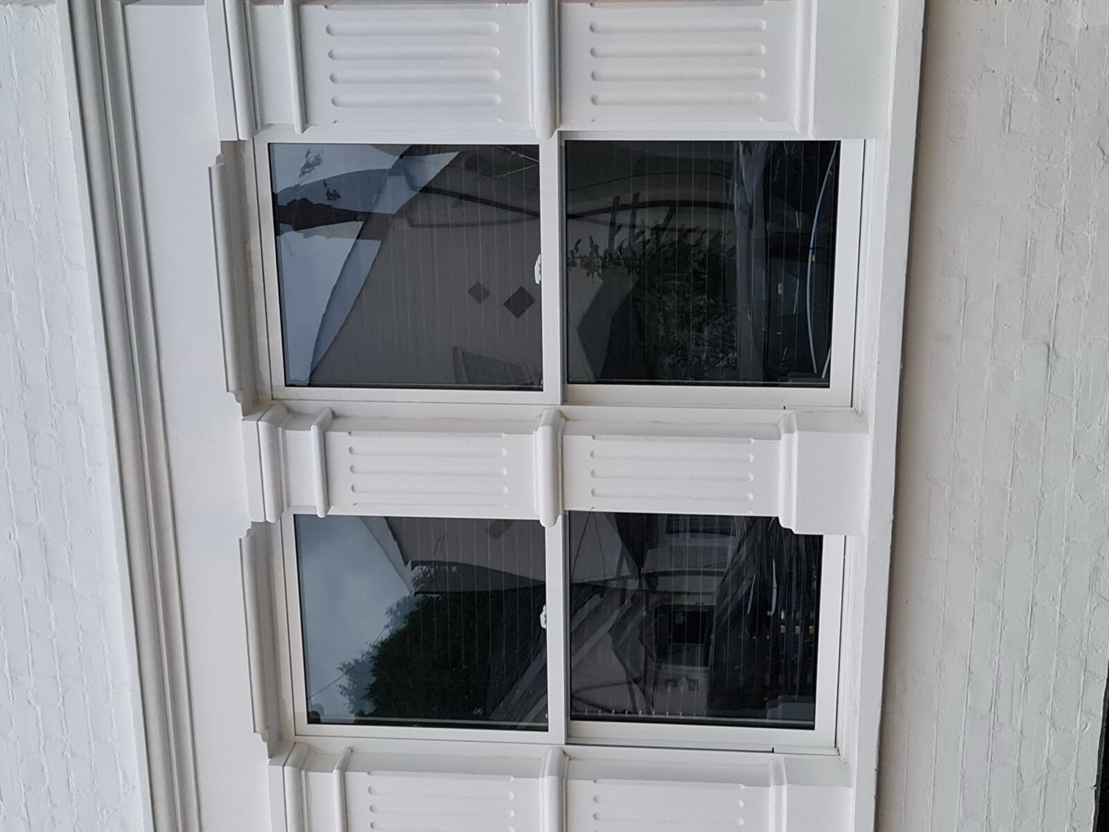 A white uPVC sash window in a painted brick wall
