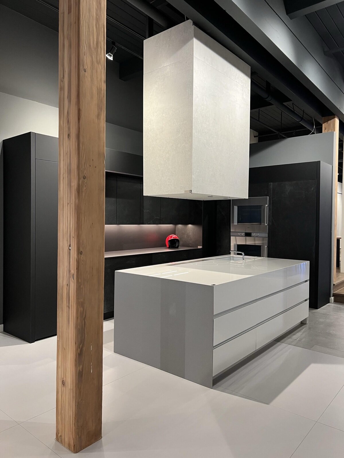 Matt black kitchen units with under cabinet lighting behind a grey island