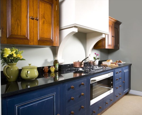 Kitchen with navy blue painted base units, black worktop and wooden wall cupboards